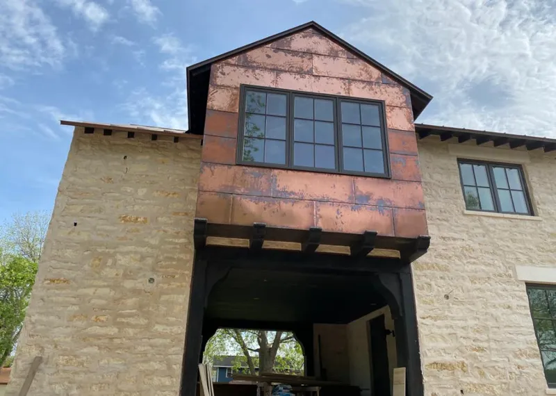 Copper metal panel facade on a stone building for Roof Repair in Cabot